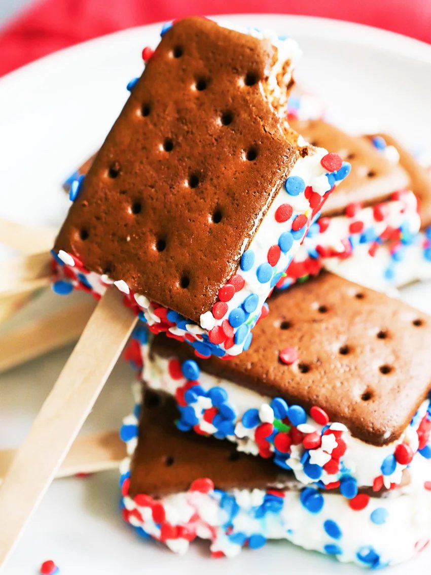 Patriotic ice cream sandwiches on a stick with red, white, and blue sprinkles for summer parties