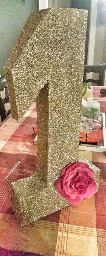 A DIY gold glitter number one decoration for a pink and gold first birthday party