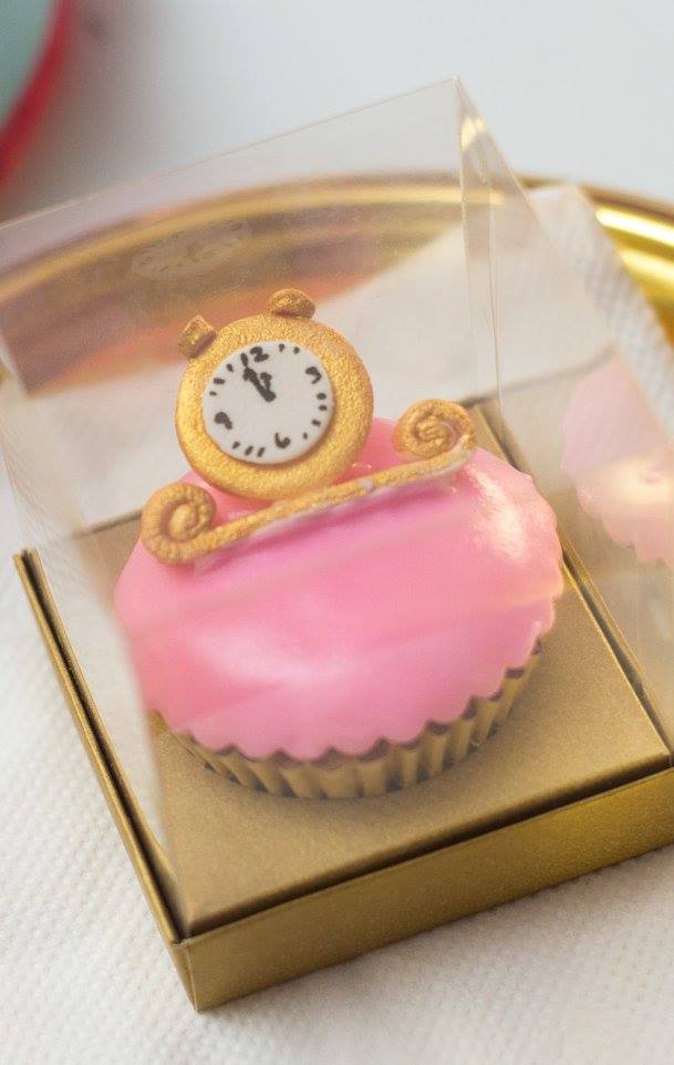 Pink cupcake favor in a box topped with a gold clock for a Cinderella party