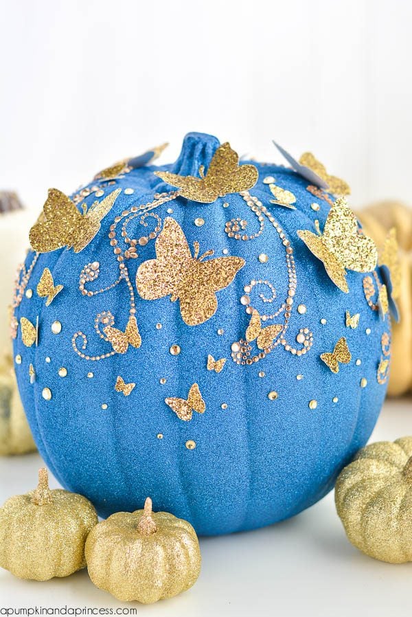 DIY blue and gold glitter pumpkin with butterflies makes the perfect Cinderella party decor or table centerpiece