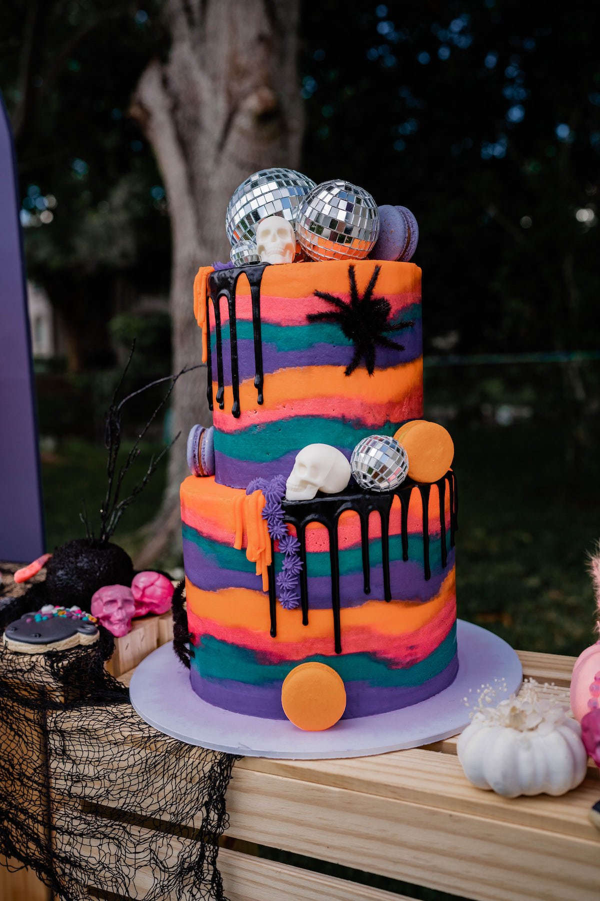Colorful Halloween drip cake with disco balls, skull heads and macaroons