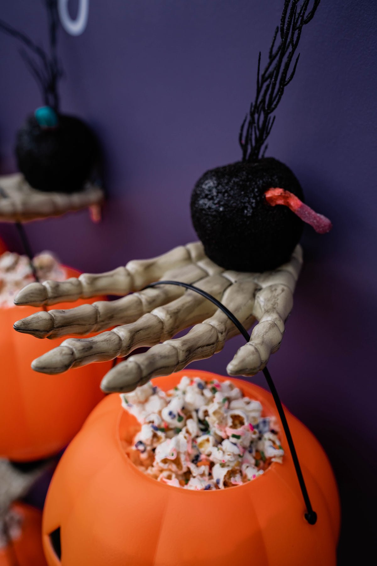 Creepy skeleton hands holding pumpkins filled with popcorn