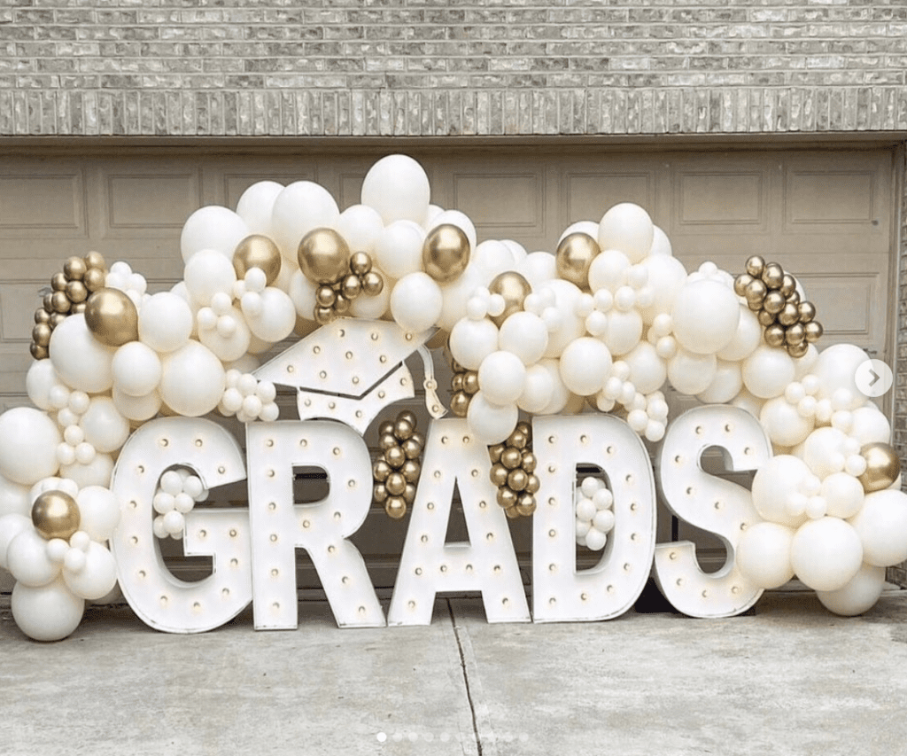 White and gold Grads marquee letters with balloons