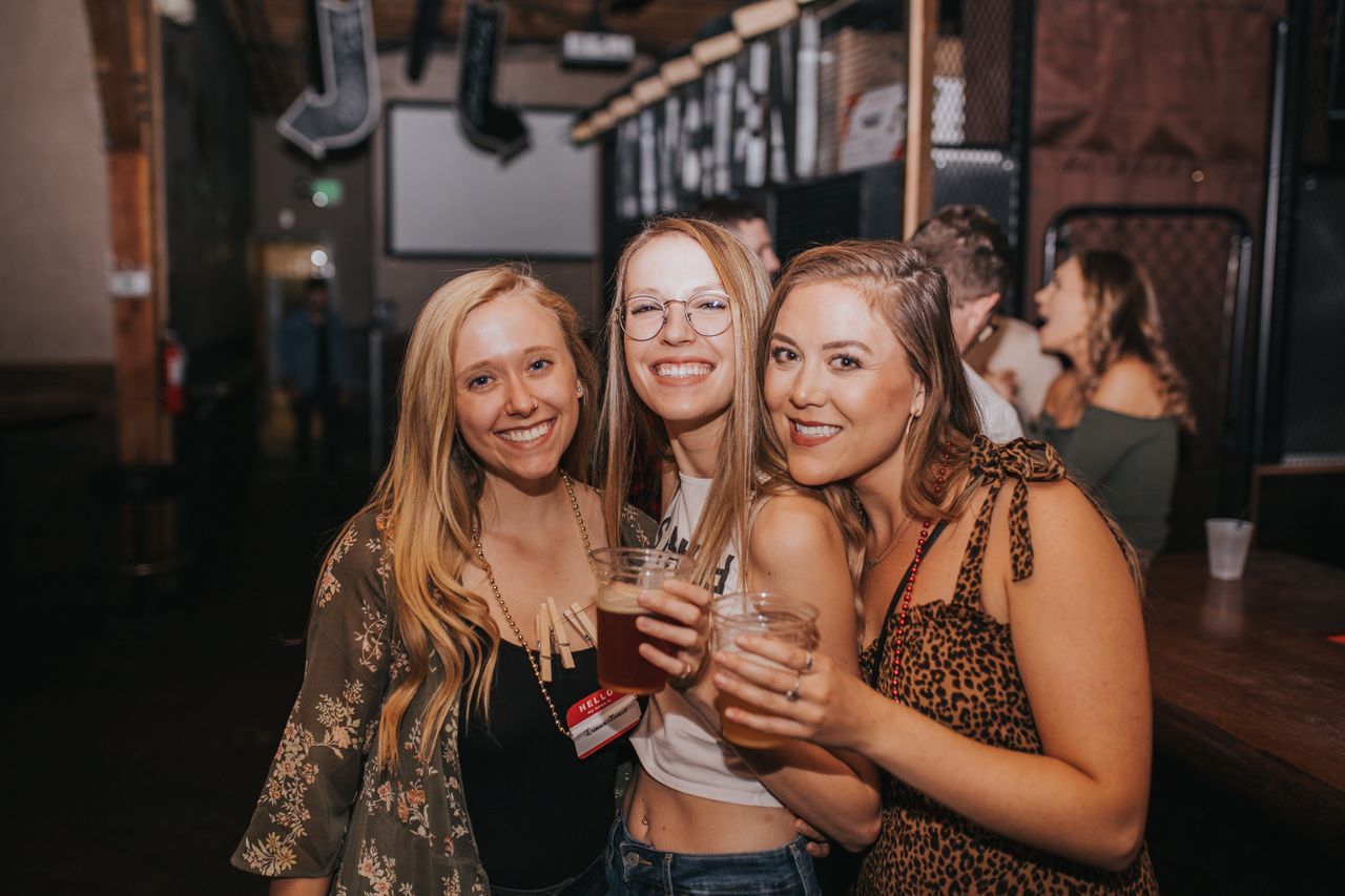 Three girls playing drinking party games at a bar mixer.
