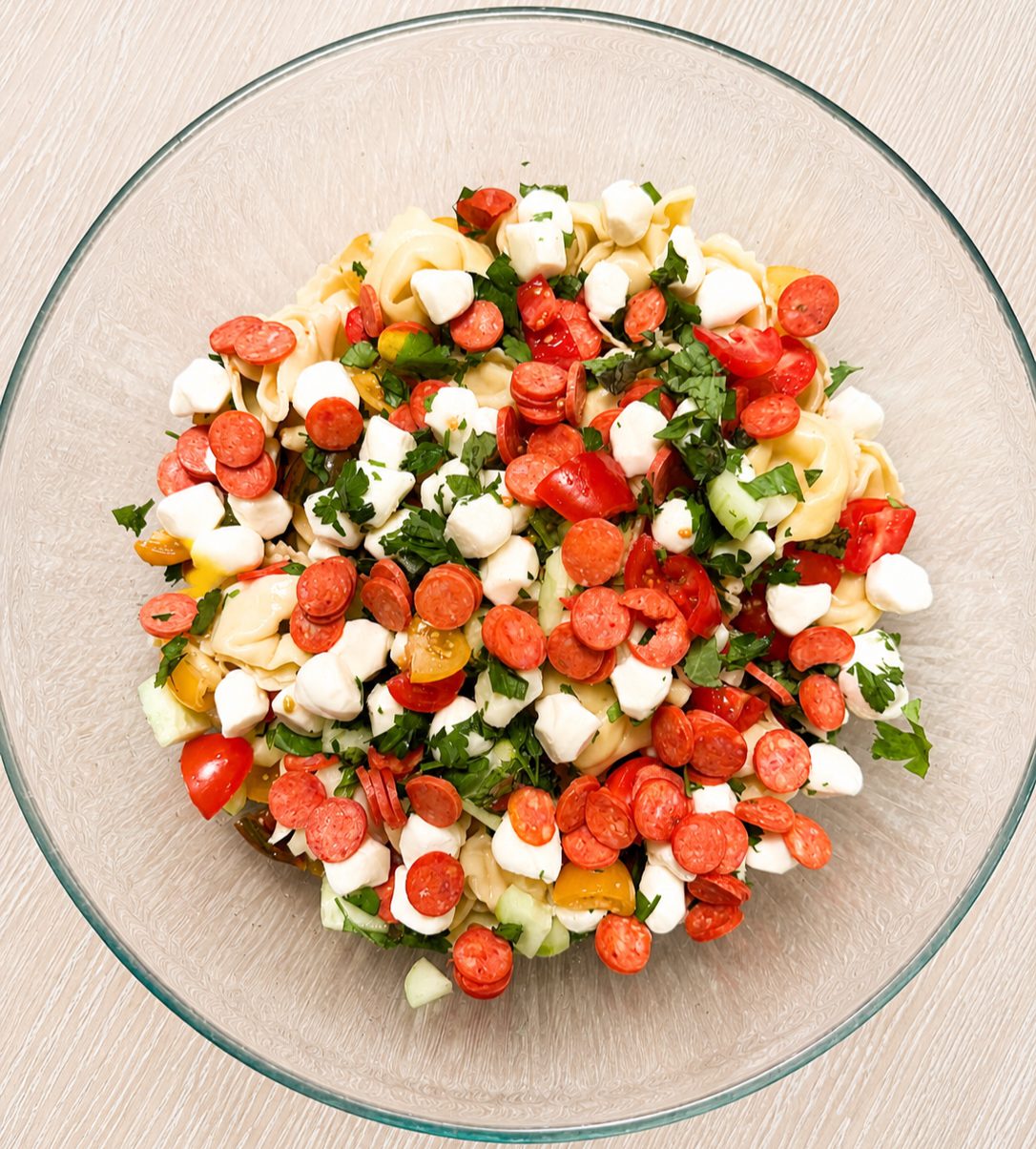 Close-up of tortellini pasta salad with fresh vegetables, feta, and tangy Greek dressing.