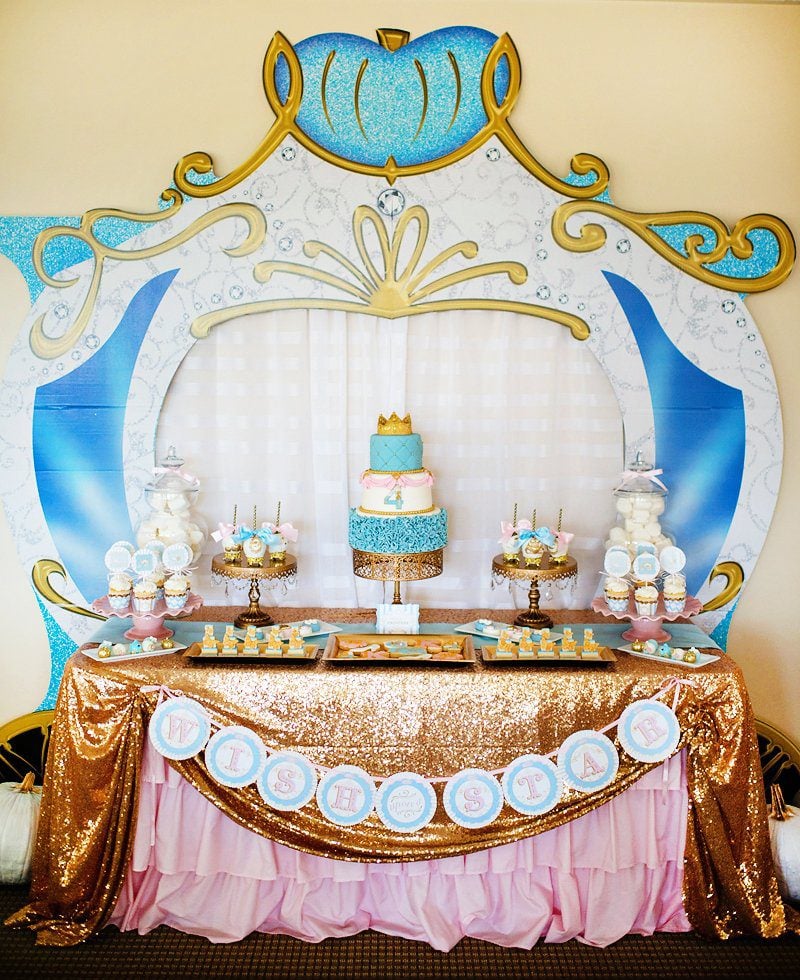 Blue, pink, and gold Cinderella carriage dessert table with a custom birthday cake, cookies, candy apples, and more